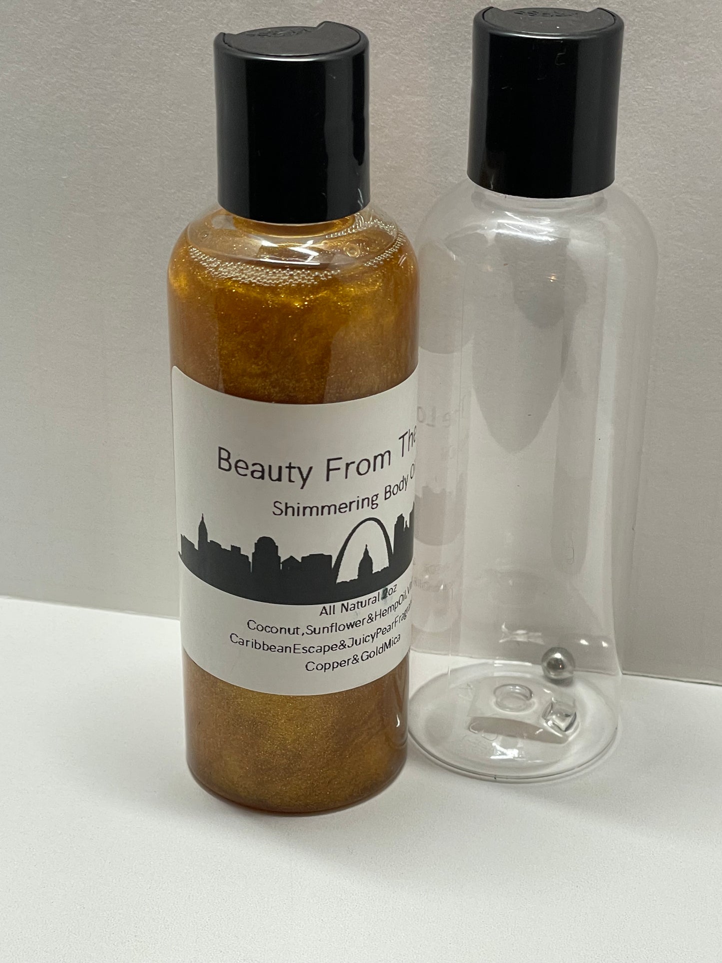 The empty 3.4 oz. bottle next to the full bottle, has the bead to help shake up that all homemade shimmer so it's a more even shine.