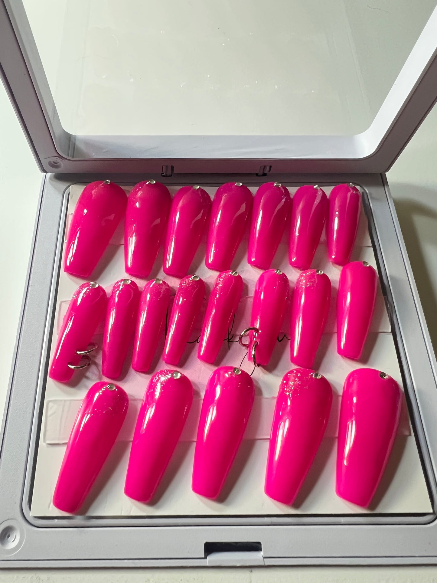 Set of 20 long coffin press-on nails with pink gel polish. Rhinestones at the cuticle and slight silver glitter (faintly) and two pierced nails with O rings & sealed with hard gel.
