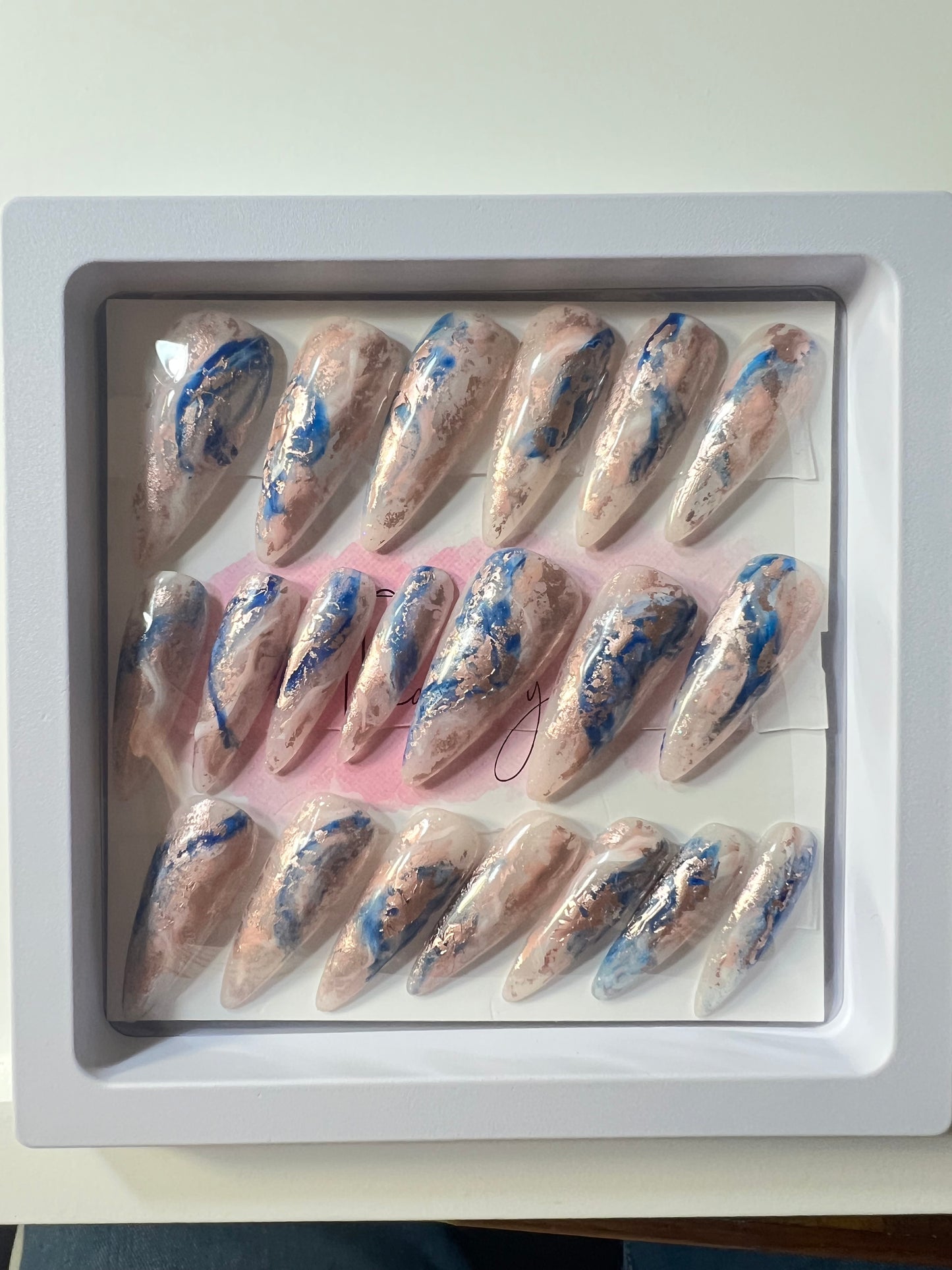 Set of 20 Long Stiletto shaped press-on nails with a layer of acrylic with hard gel over that. Gel polish; rose, white and blue marbled and hard gel top coat