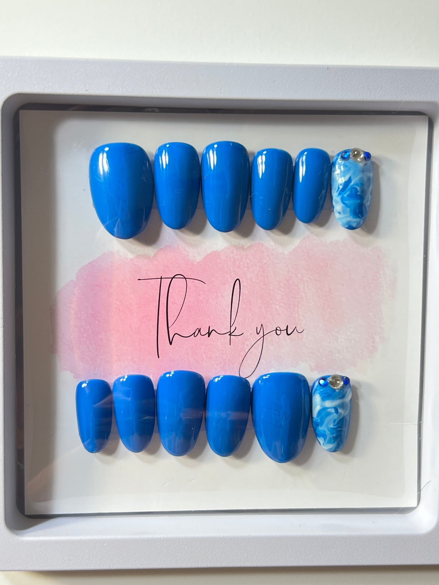 Size large, natural short round shape with 2 accent nails with blue and white marbling and stones by the cuticle.