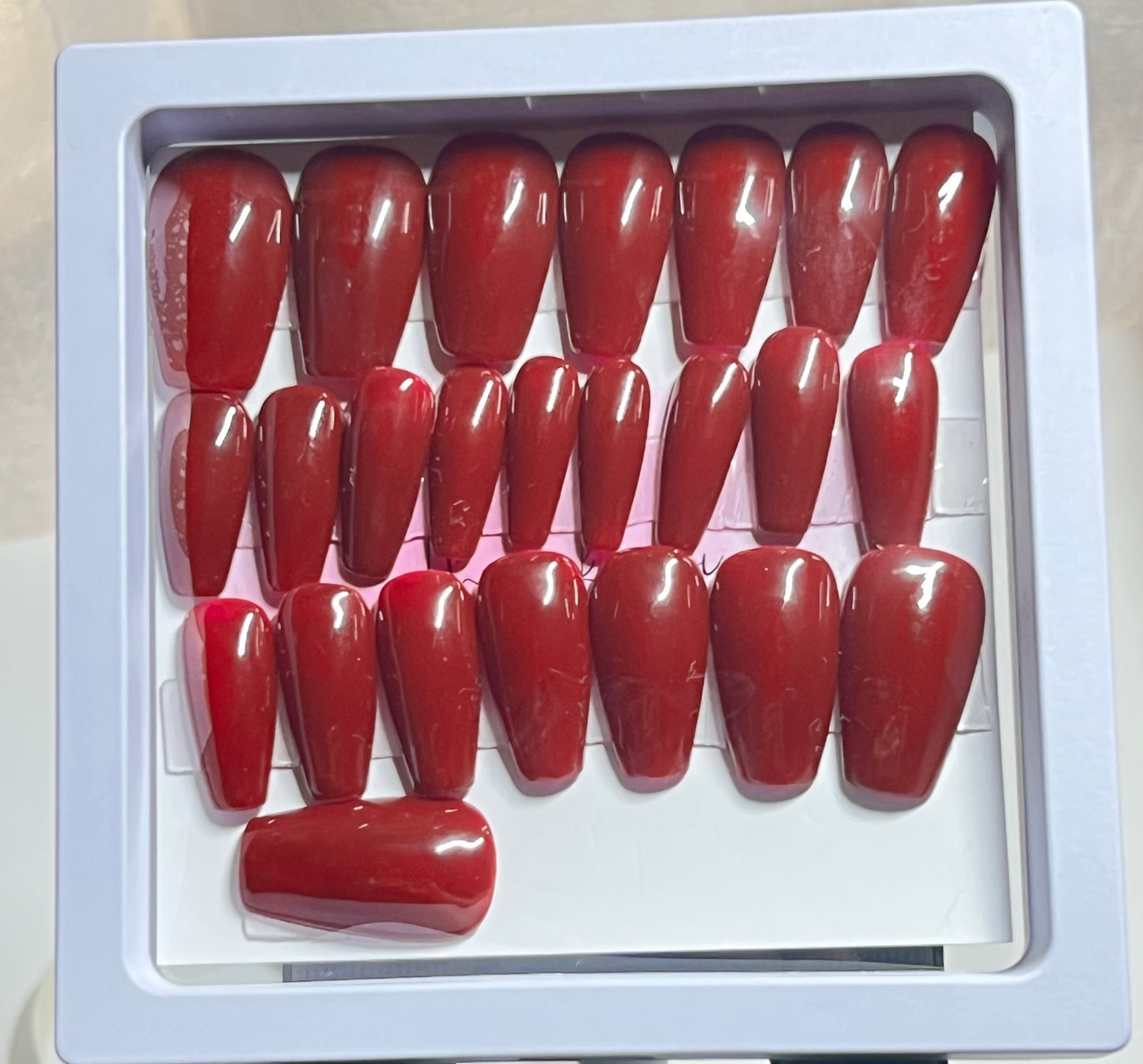 Set of 24 Medium length natural coffin press-on nails with a deep red brick gel polish and no stain top coat.