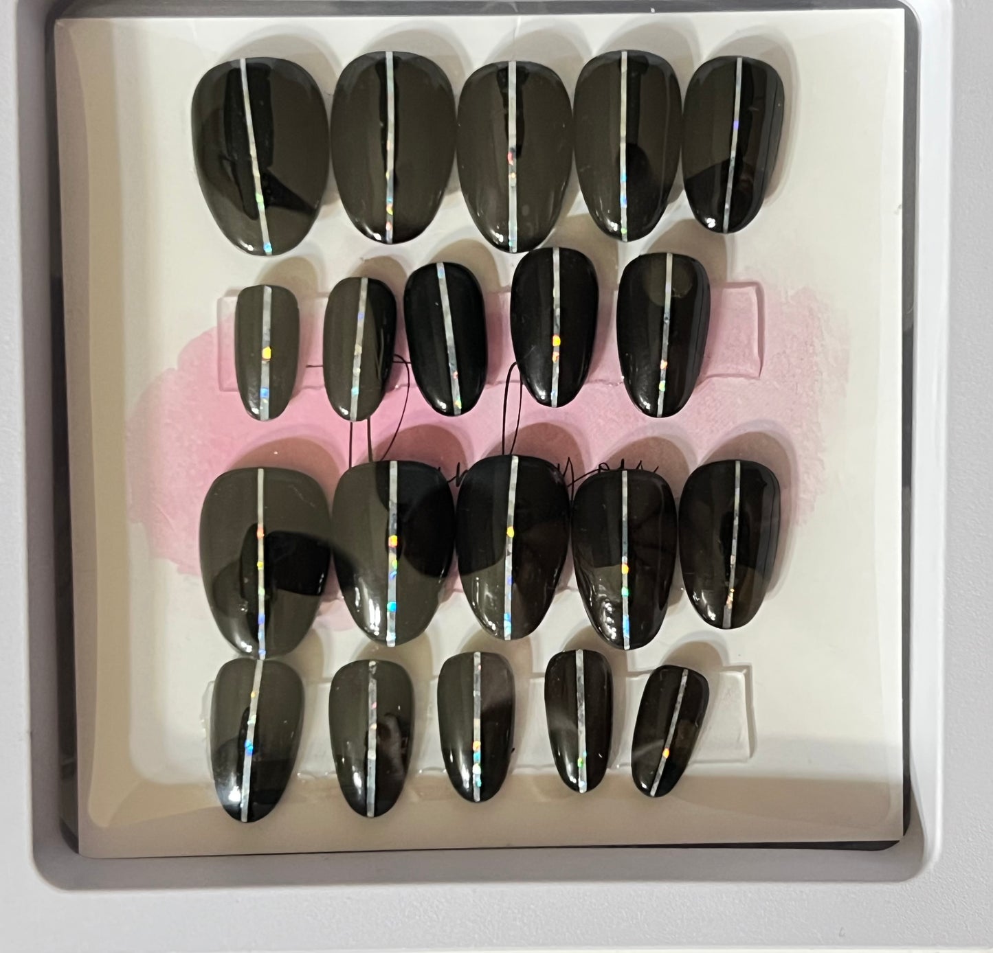 Set of 20 natural short round press-on nails with black gel polish and a pin stripe down the center.