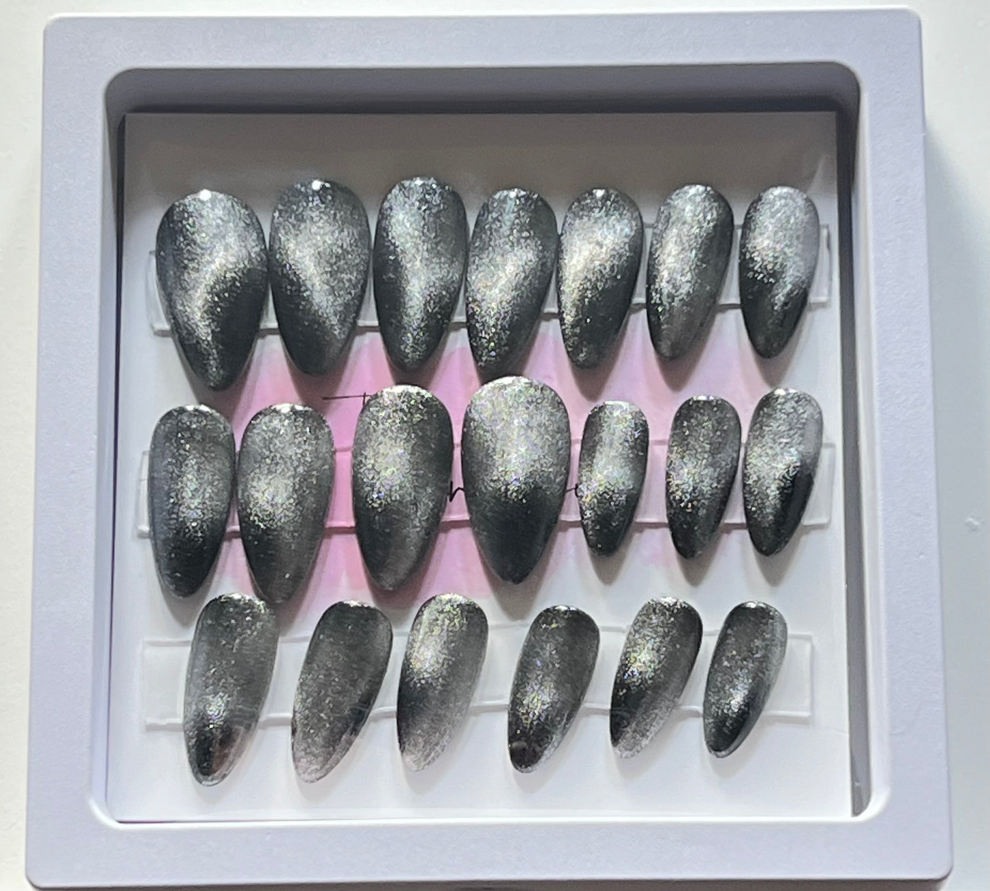Set of 20 short almond press-on nails with black gel polish and silver cat eye over the black. No stain top coat.