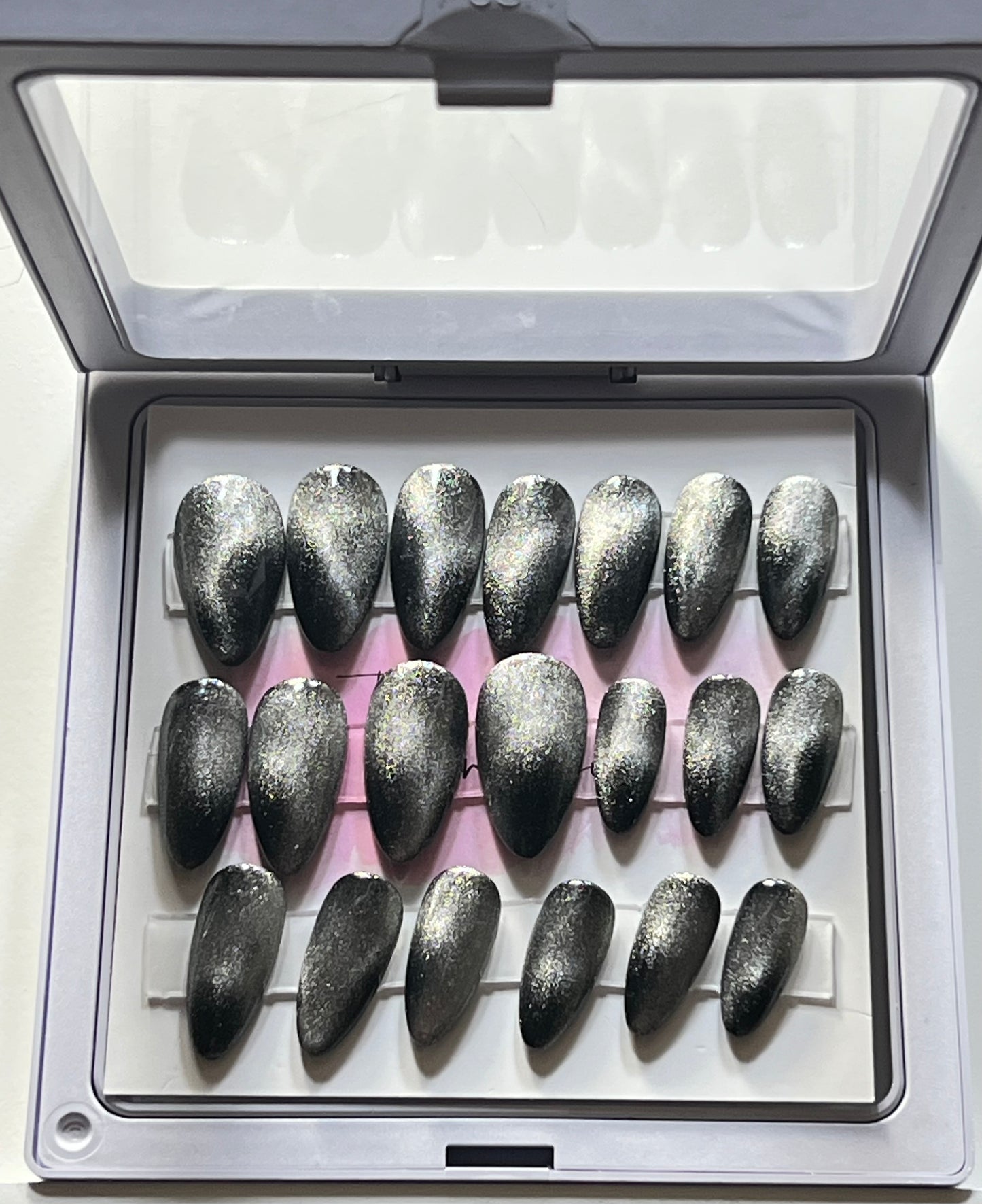 Set of 20 short almond press-on nails with black gel polish and silver cat eye over the black. No stain top coat.