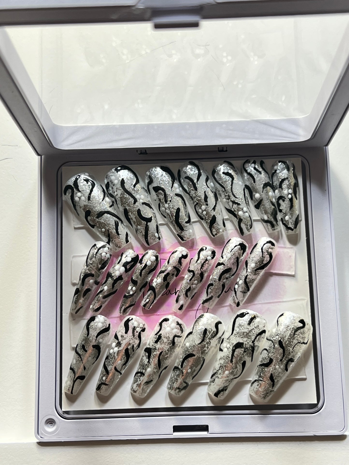 Set of 20 long coffin nails with milky white /w silver foil & black and white dots and swipes on all. Gel polish and 2 coats of no stain top coat.