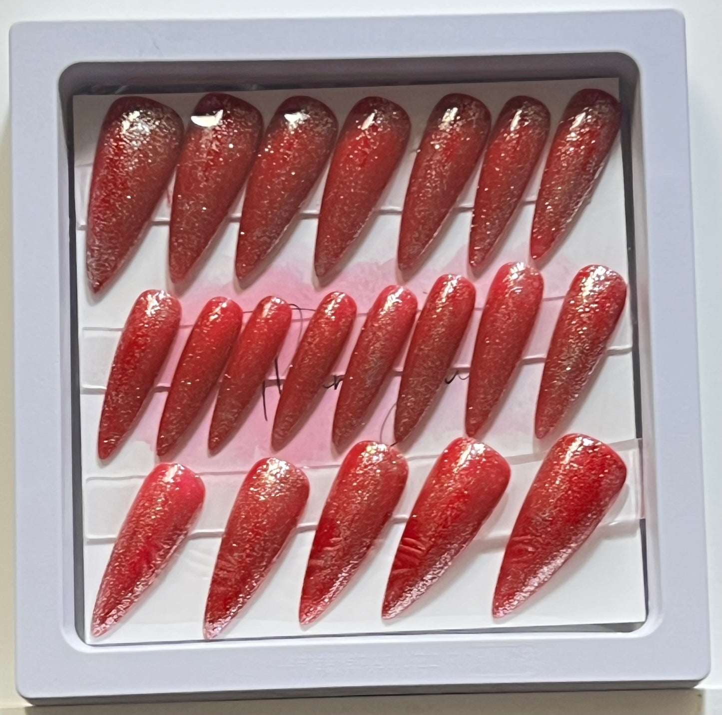 Set of 20 long stiletto nails with red gel polish and silver glitter over. No stain top coat.