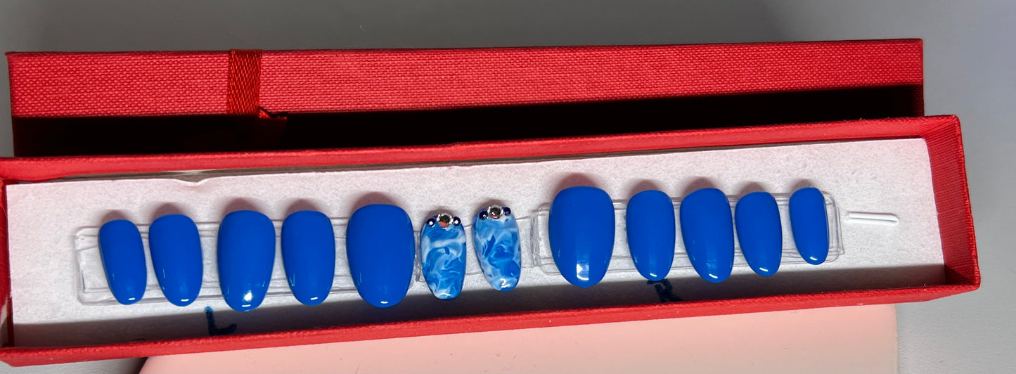 Hand painted Short Round Nails with a great blue gel polish and 2 accents with white and blue marbling and few stones around the cuticle.