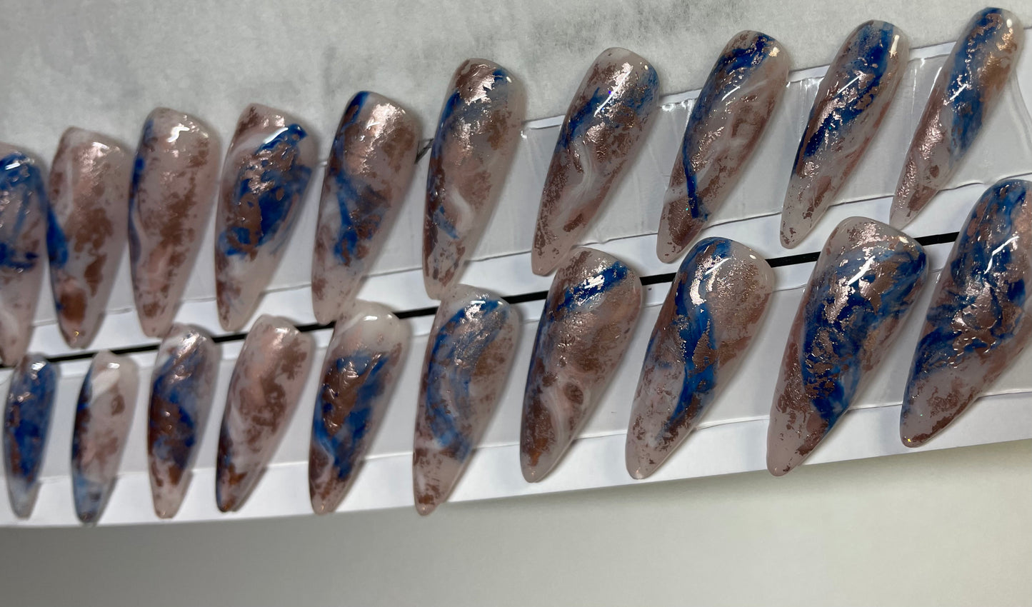 Professionally created set of press-on nails. I applied a soft pink acrylic later under a hard gel base coat. Fun milky look with blue and a goldish foil. A light swish of light white accent throughout all nails.