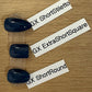 Three glossy dark blue press-on nails in different shapes (short stiletto, extra short square, short round) arranged vertically on a wooden surface with white labels pointing to each style.