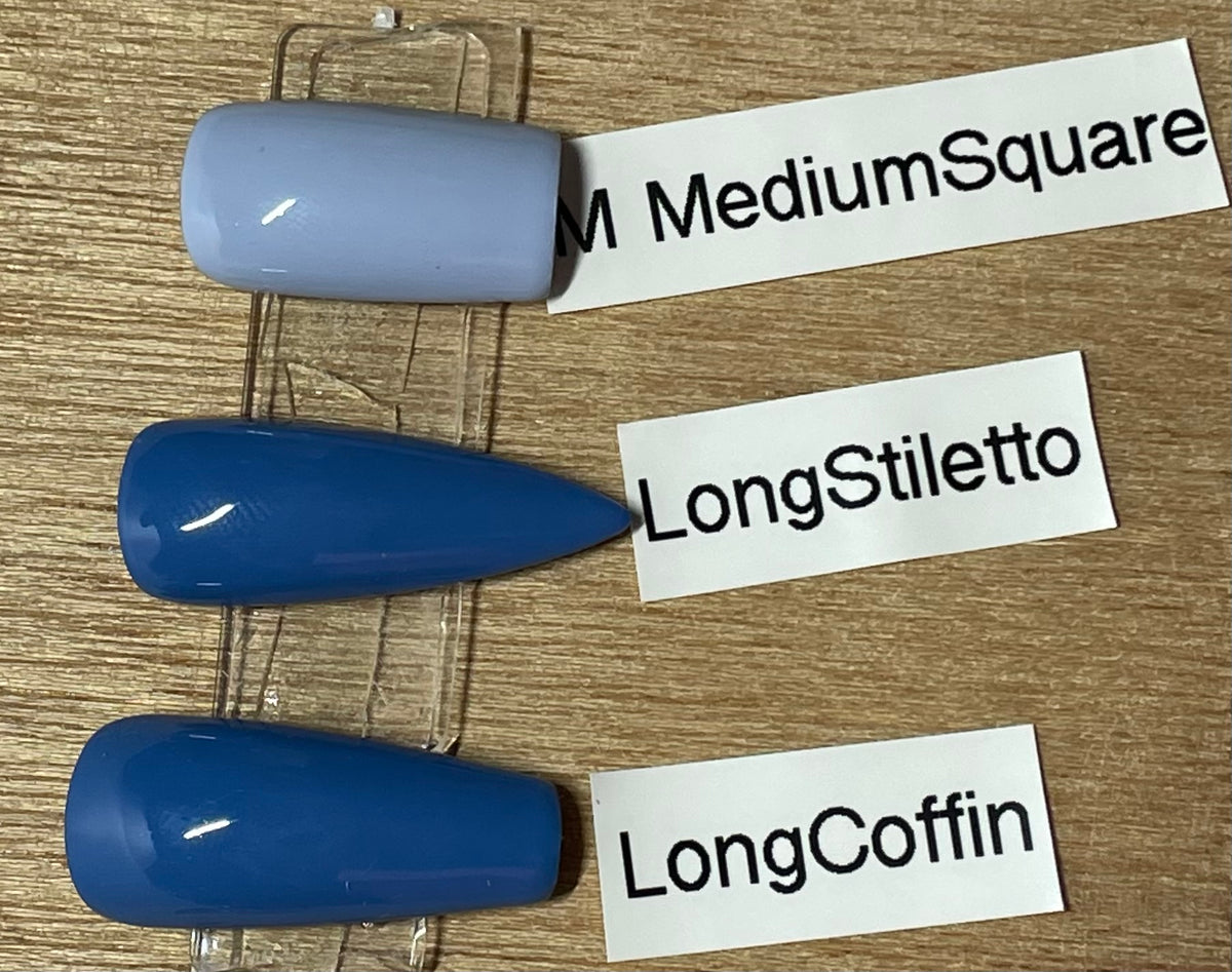 Three artificial nail tips in different shapes and lengths displayed on a clear stand over a wood surface, with handwritten labels reading MediumSquare, LongStiletto, and LongCoffin.