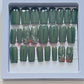 Set of 24 medium length square nails and 4 accent nails with hand painted holy with a sprinle of gold glitter. The other 20 nails are a solid dark green gel polish and not stain top coat.