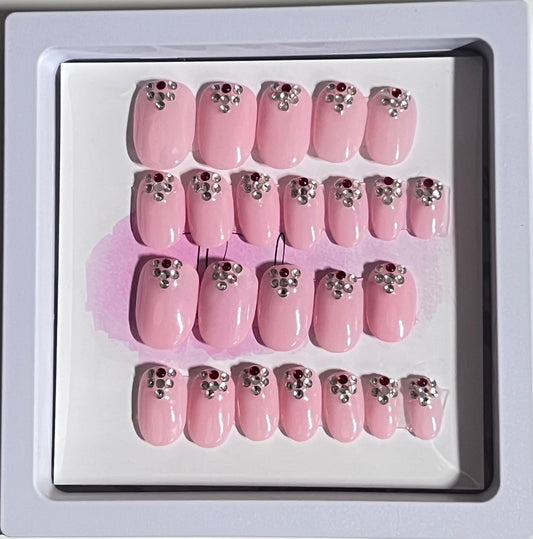 Set of 24 extra short oval nails with a light pink gel polish and stones at the cuticle sealed with a hard gel top coat. 