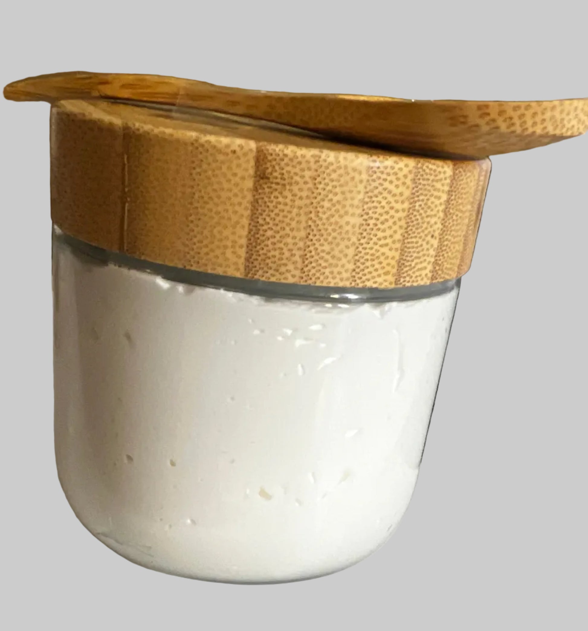 10 oz Glass jar of body butter with bamboo spoon on top for application.