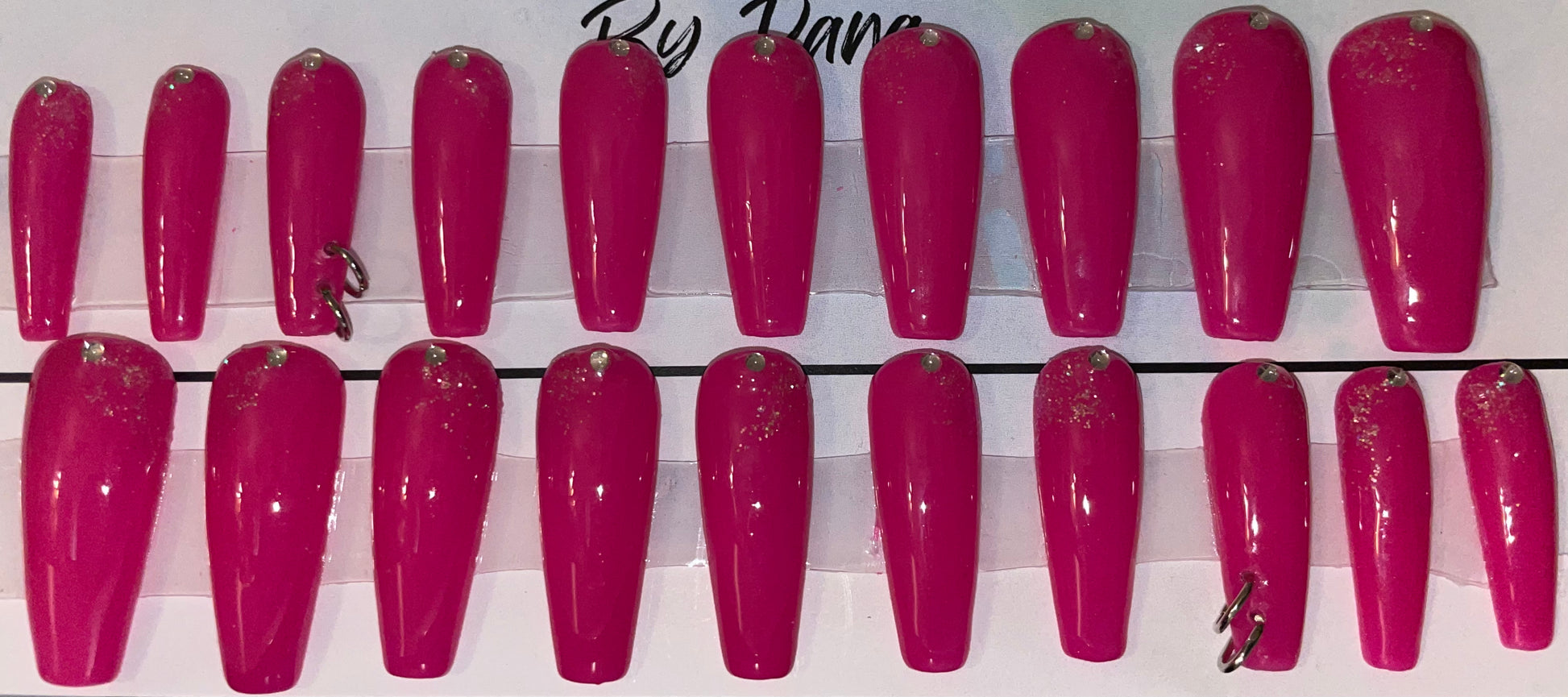 Professionally hand painted with a gorgeous pink gel polish. Added stones at the cuticle with silver glitter around parts of the stones. I pierced 2 nails and put 2 jump rings in each.