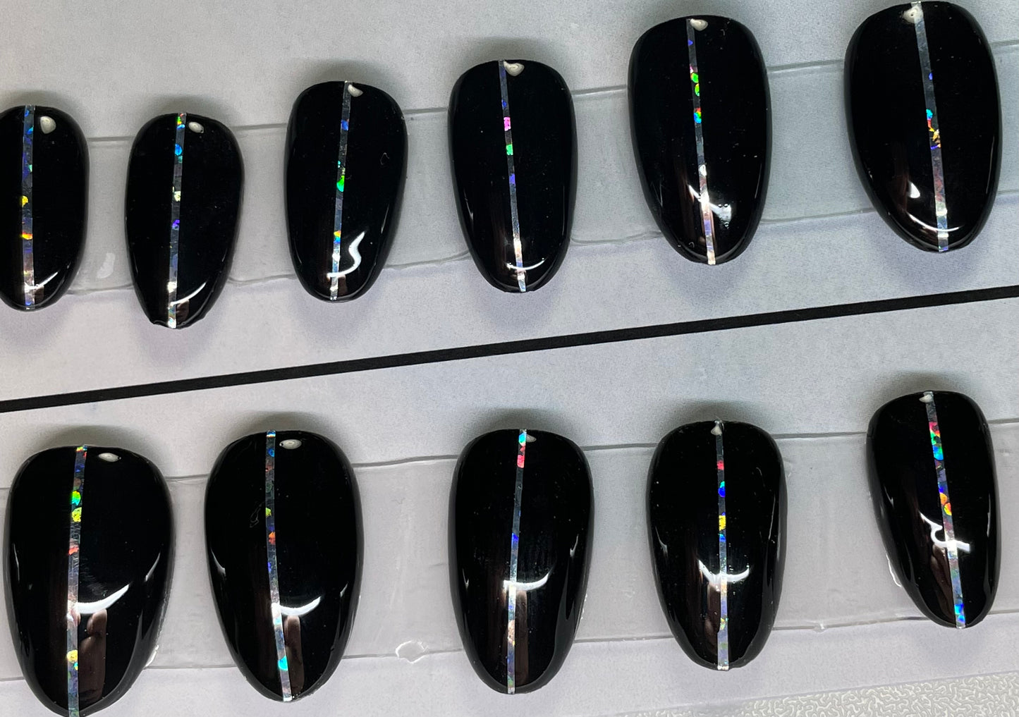 Hand painted with black gel polish set. A holographic pin stripe down the center is a great look. Short round for the active and on the go person.