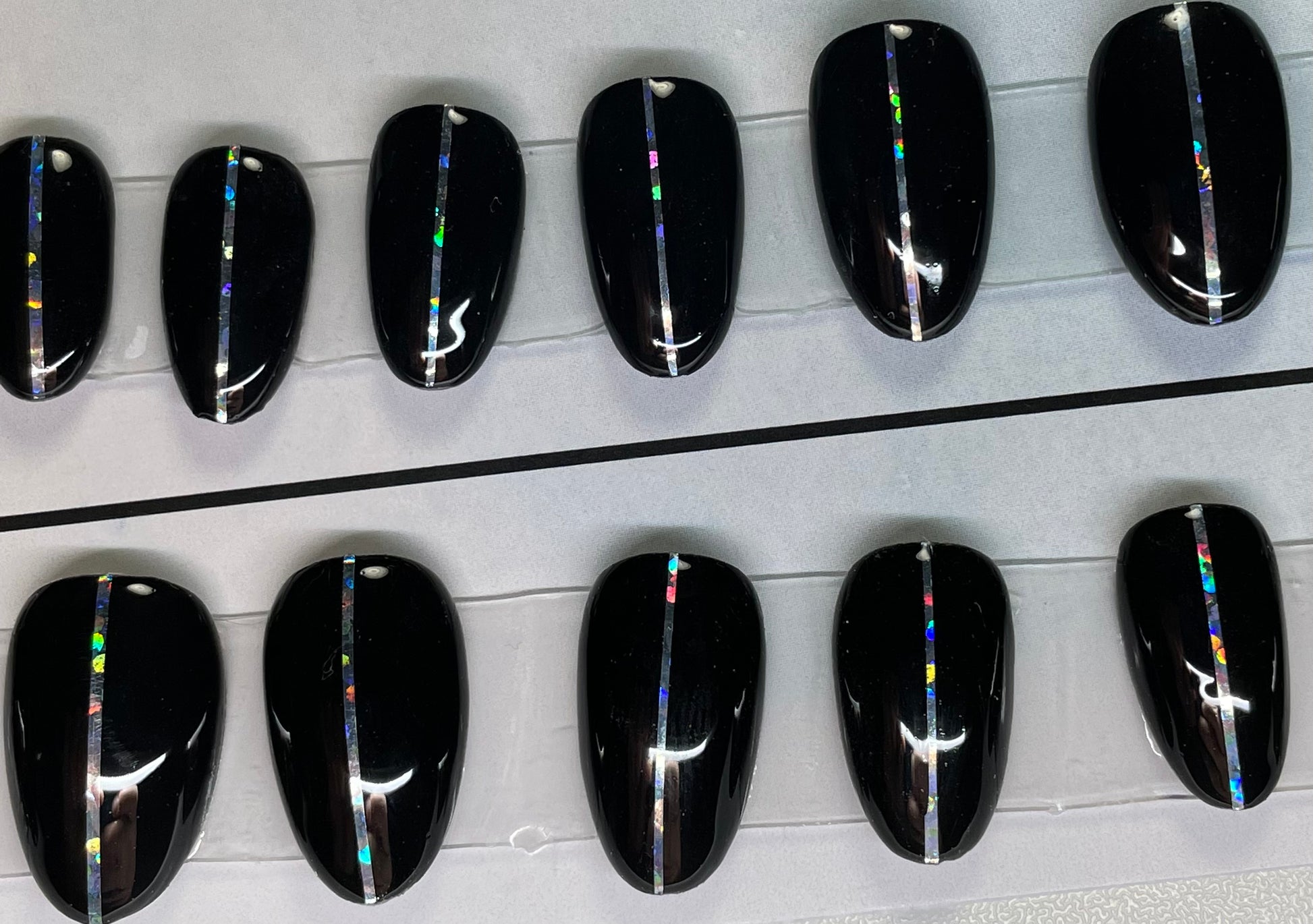 Hand painted with black gel polish set. A holographic pin stripe down the center is a great look. Short round for the active and on the go person.