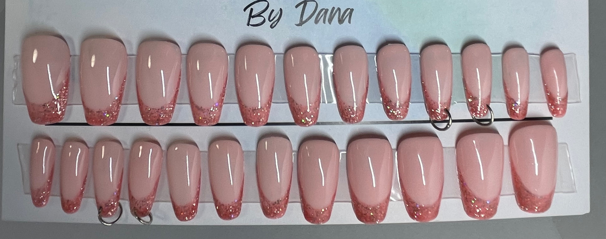 Professionally hand painted pink french nails. Set of 24 nails. 4 accents are pierced and have a jump ring in them. Secured with hard gel.