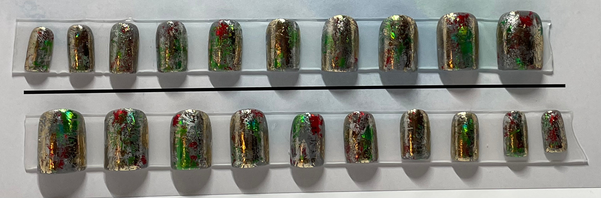 Set of 20 professionally hand painted holiday nails. Red, Green, Gold and Silver Foil over gray gel polish.